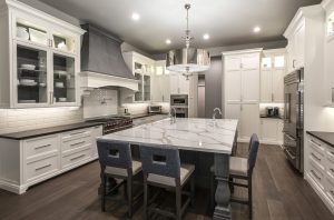 Bright, modern kitchen design with white cabinets and black countertops, marble island, and dark wood floors.