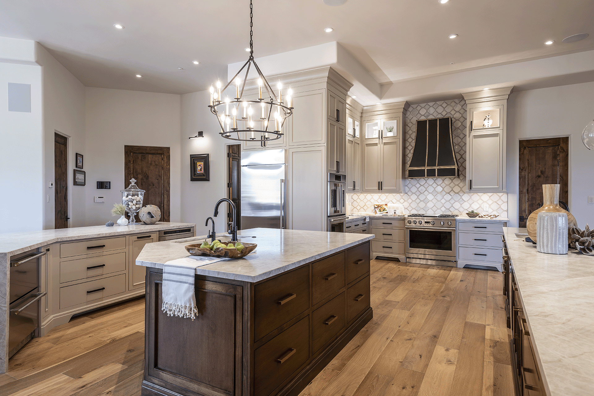 Neutral colored kitchen with beige cabinets, wood island with white countertop, hardwood floors, stainless steel appliances.
