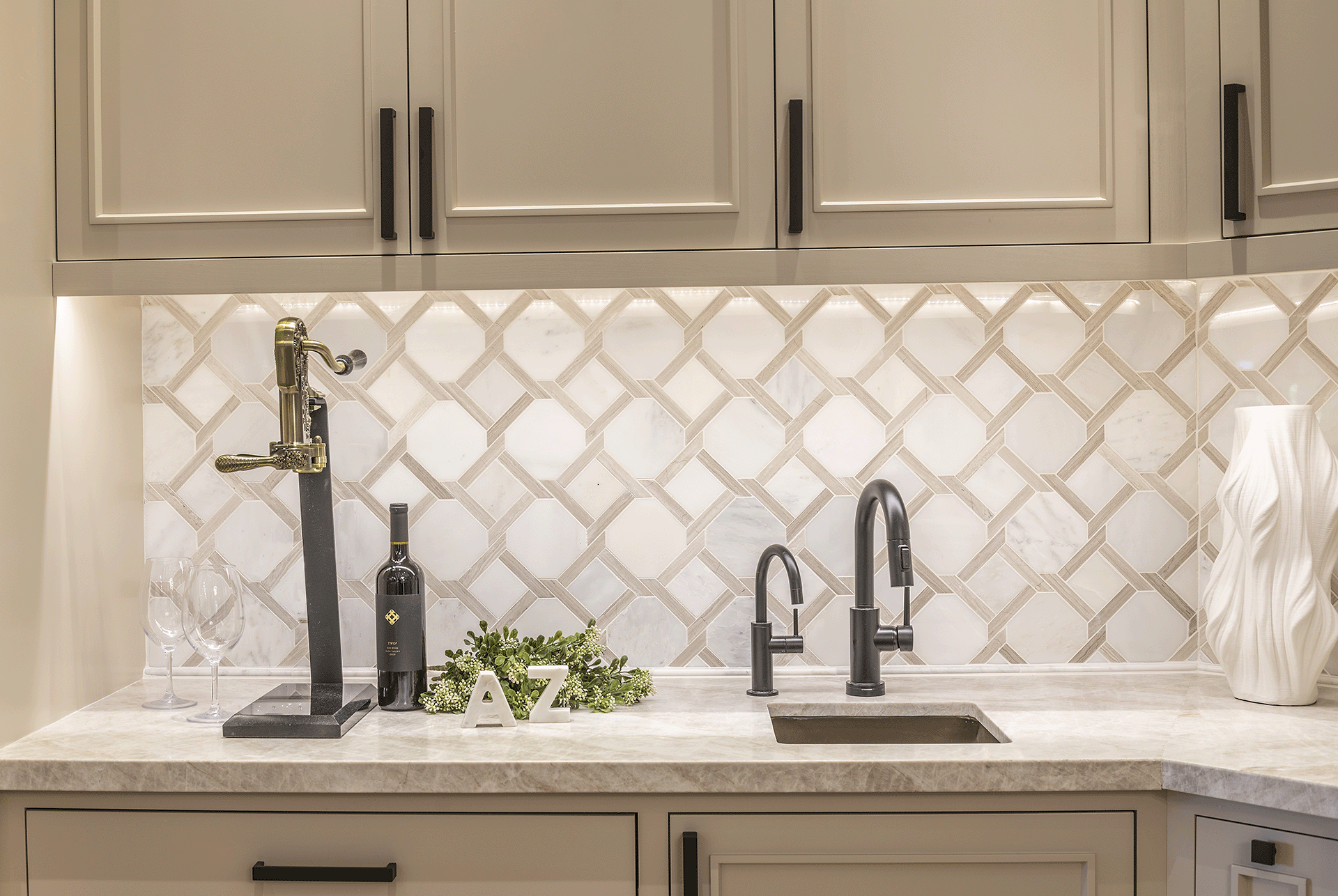 Neutral cream and white kitchen cabinets and countertop, backlit with black accents.