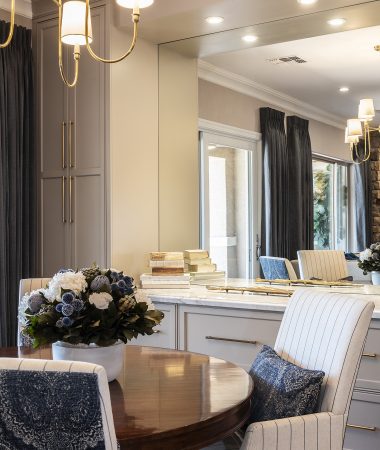 Round table with floral arrangement, chandelier, and chairs with pinstripe covers.