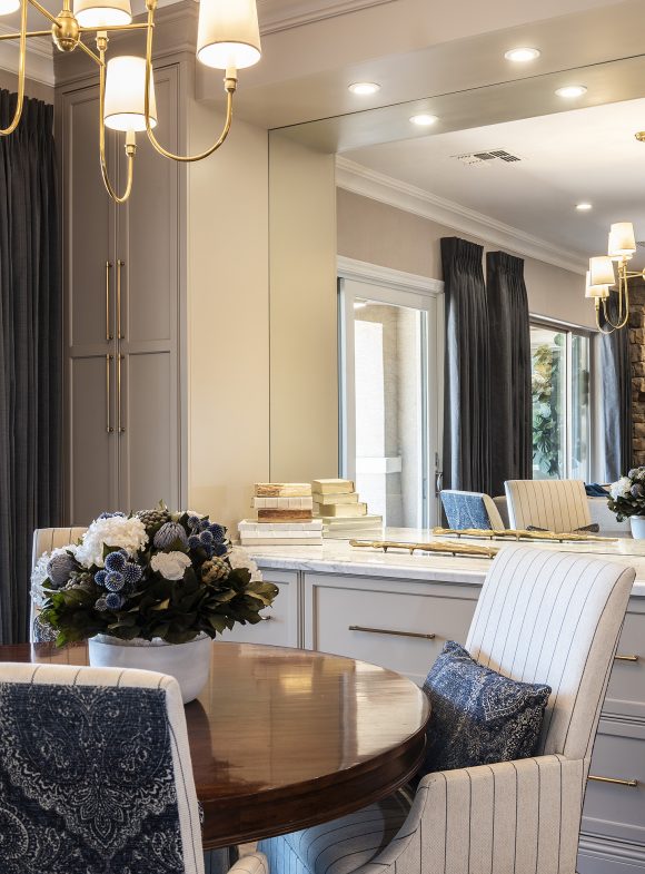 Round table with floral arrangement, chandelier, and chairs with pinstripe covers.