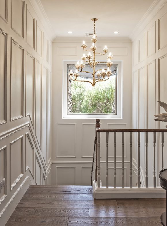 Chandelier above stairwell, bright white interior with window.