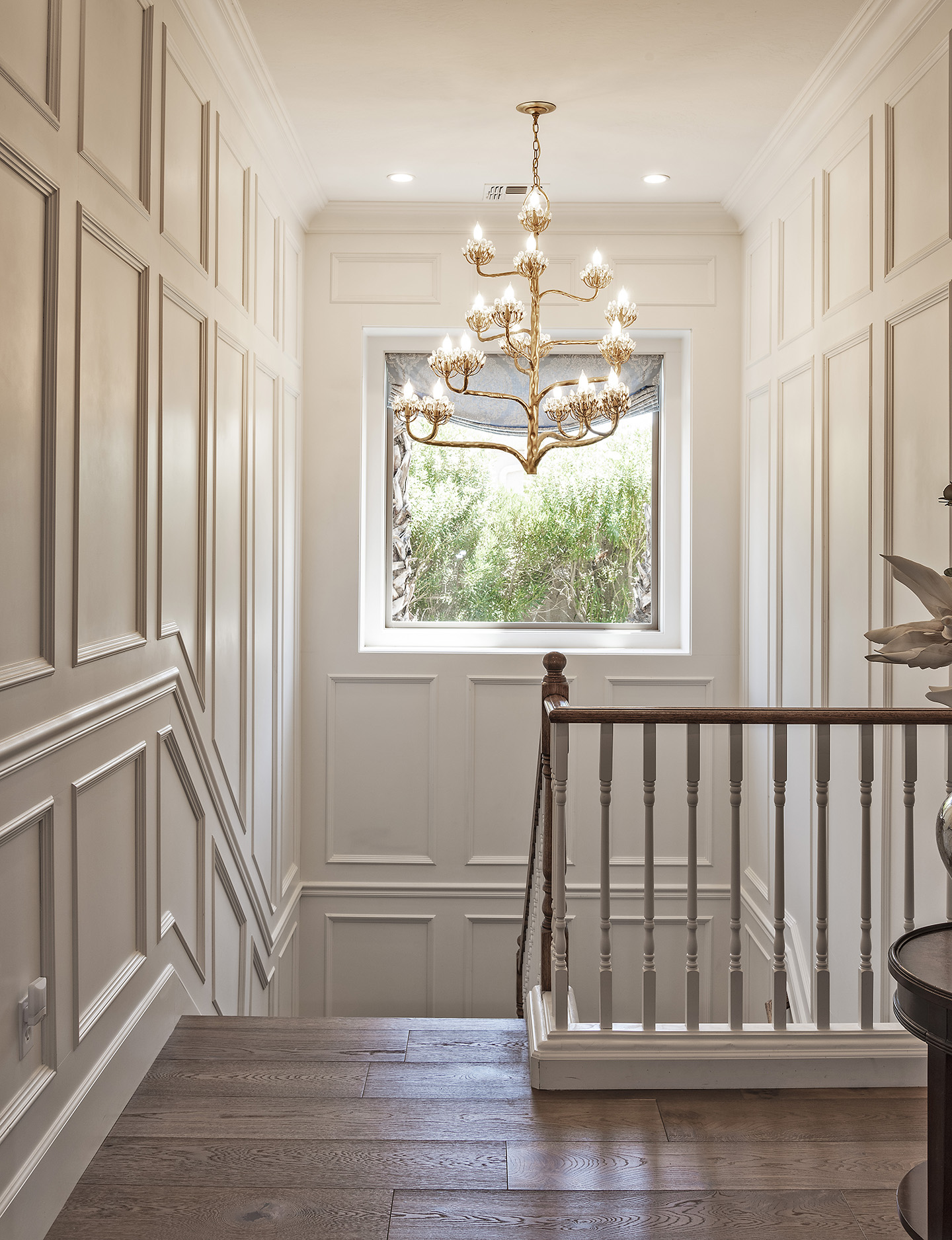 Chandelier above stairwell, bright white interior with window.