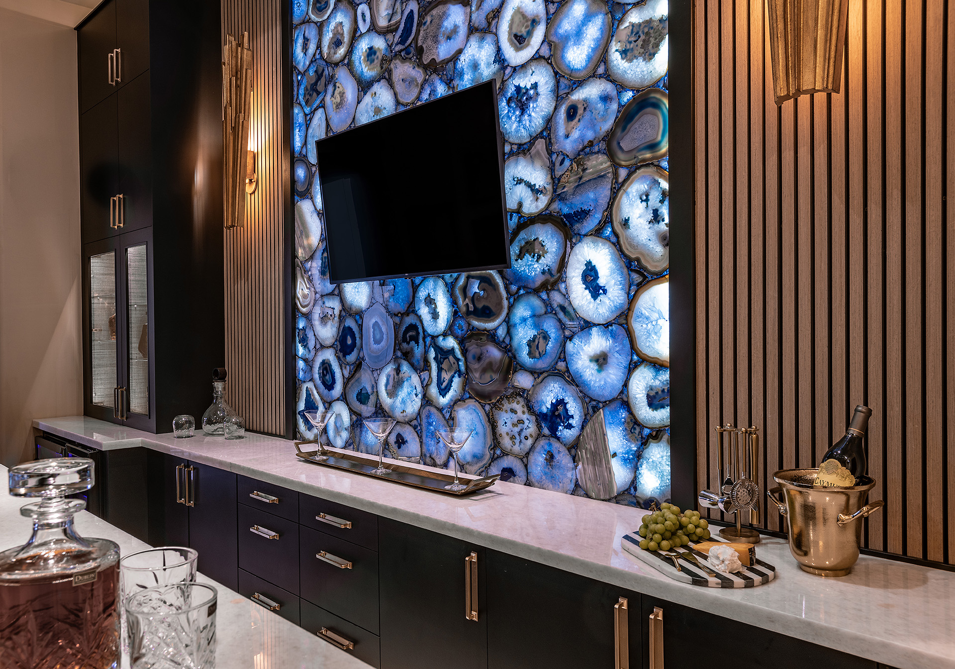 Bar Area with T.V. mounted on a backlit design, black cabinets and white countertop.
